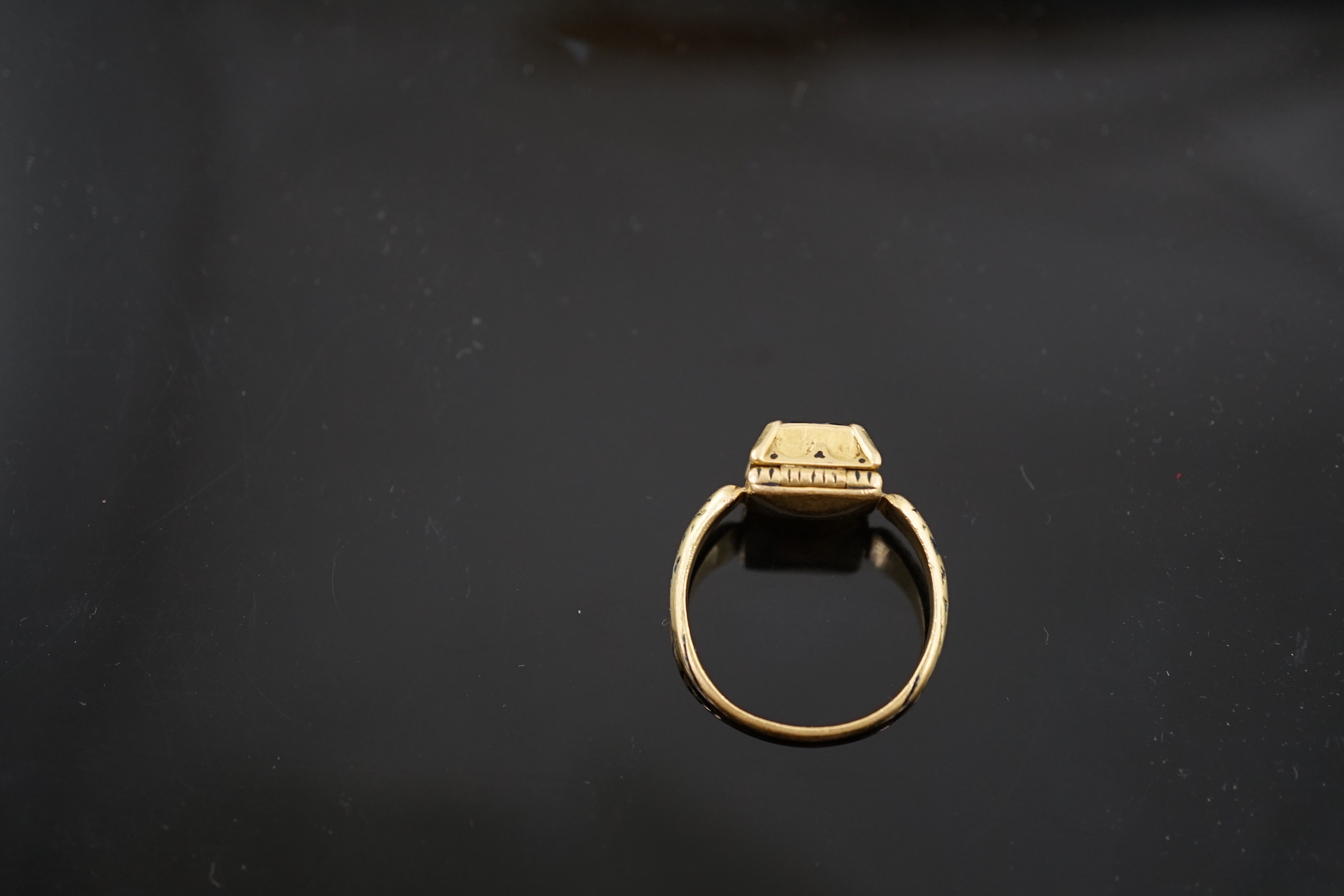 An antique high carat gold, black enamel and collet set cushion cut sapphire set 'poison' ring